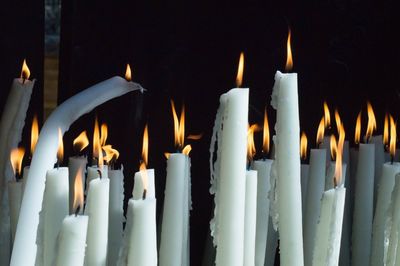 Close-up of burning candles against black background