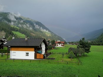 Houses on field by mountain against sky