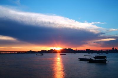 Silhouette boats sailing in sea against sky during sunset