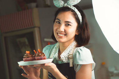 Portrait of smiling young woman holding cake