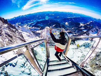 High angle view of man standing at observation point over mountains against sky