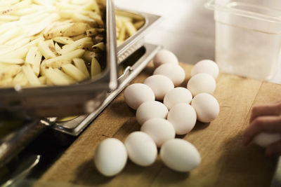 High angle view of eggs and potato slices on counter in commercial kitchen