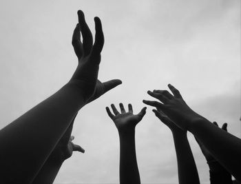 Cropped hands of people against sky