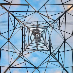 Low angle view of electricity pylon against blue sky