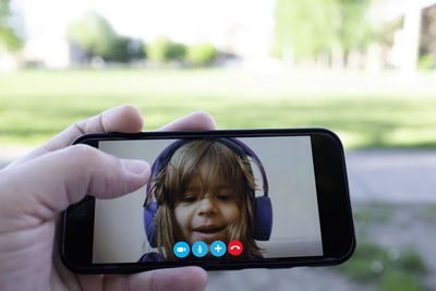 Cropped hand of person video calling with girl over smart phone