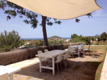 Empty chairs and table on beach against clear sky