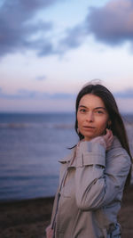 Portrait of young woman looking away against sea