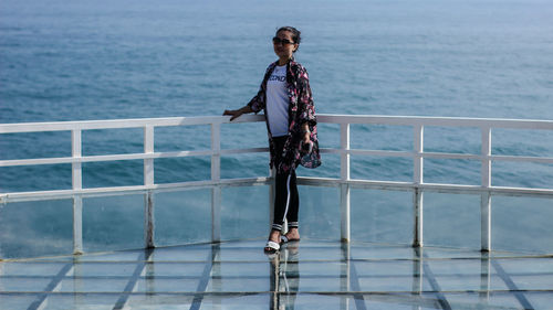 Man standing on railing against sea