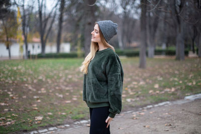 Full length of young woman standing against trees