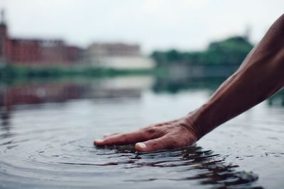 Cropped image of person touching water in river