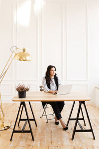 Young woman using laptop while sitting on chair at home