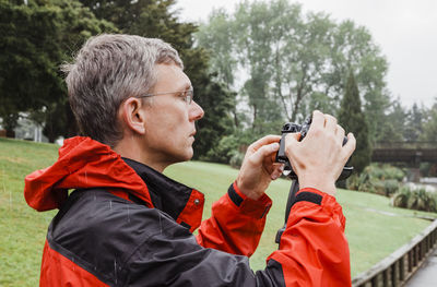 Mature man photographing with camera outdoors