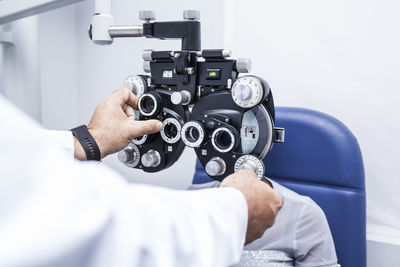 Optometrist adjusting the optometry equipment during study of the eyesight of a black woman