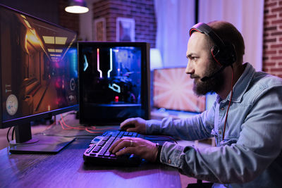 Side view of man using laptop at office