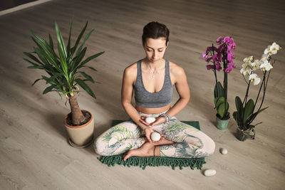 Woman doing meditation at yoga studio in the middle of flowers