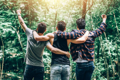 Rear view of friends standing in forest