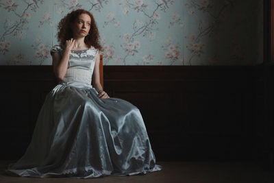 Young woman standing against wall