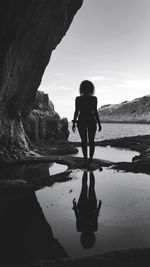 Rear view of woman standing on rock against sky