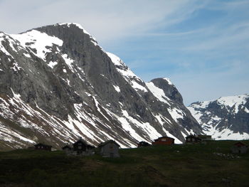 Houses on field against snowcapped mountains