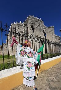 Low angle view of woman against building against clear blue sky