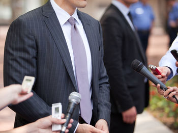 Cropped hands of female journalist interviewing man on street