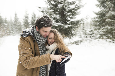 Happy woman standing on snow covered trees during winter