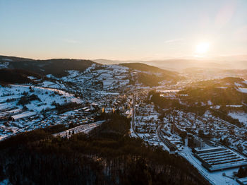 Landscape of a town and hills under snow with sunset