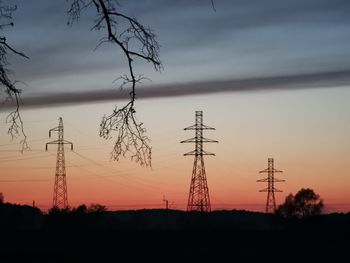 Low angle view of silhouette electricity pylon against sky during sunset