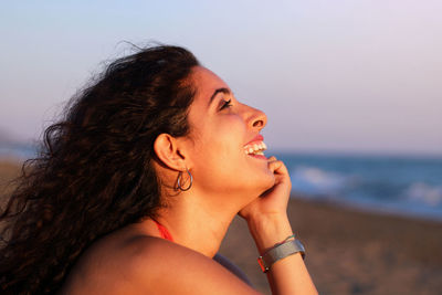 Portrait of smiling woman at beach against sky