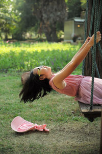 Cheerful girl siting on swing at park