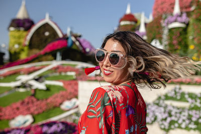 Close-up of young woman tossing hair in ornamental garden 