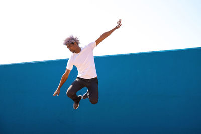 Full length of teenage girl jumping against clear sky