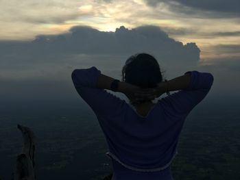 Rear view of woman standing against sky during sunset