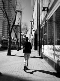 Rear view of woman walking on street amidst buildings
