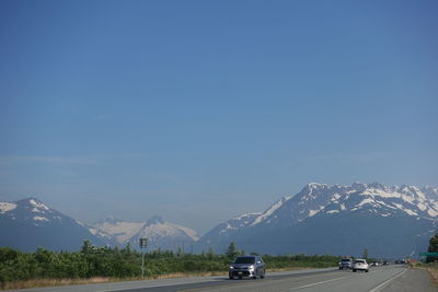Cars on road by mountains against sky