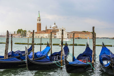 Gondolas moored at grand canal by santa maria della salute against sky