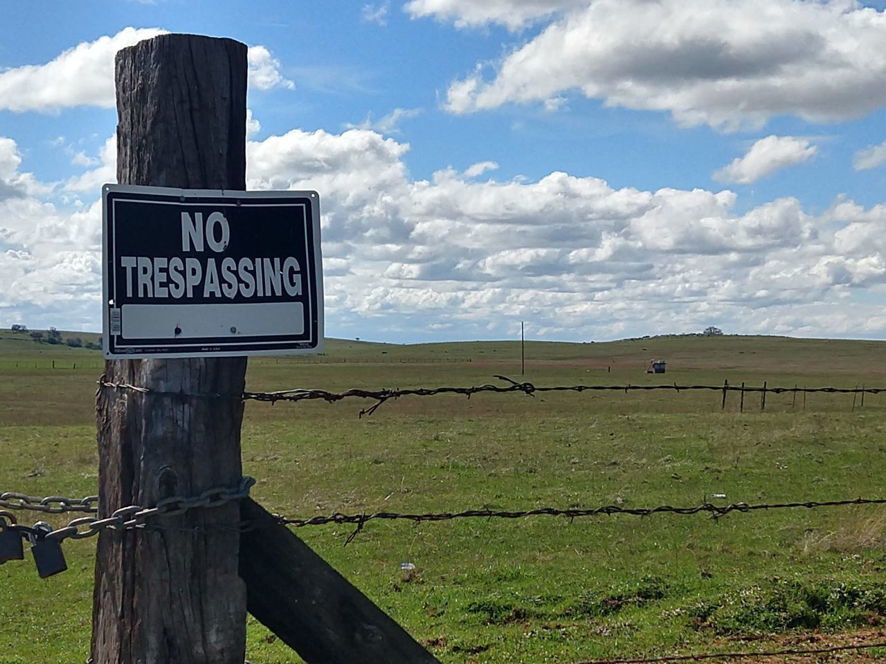 INFORMATION SIGN ON WOODEN POST ON FIELD