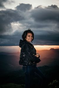 Portrait of young woman standing against sky during sunset