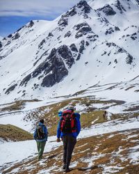 Rear view of people walking on snowcapped mountain