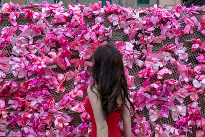 Midsection of woman standing by pink flowers