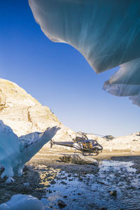 Helicopter landed just outside the entrance of a glacier cave.