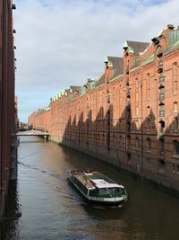 Canal amidst buildings in city against sky