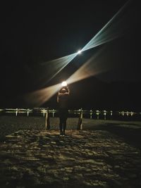 Rear view of man standing on footpath at night