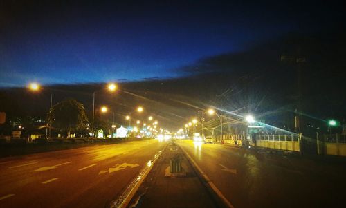 Illuminated road against sky at night