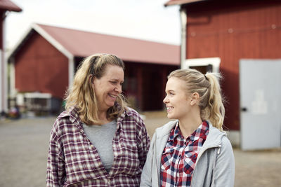 Smiling mother and daughter looking at each other while standing in farm