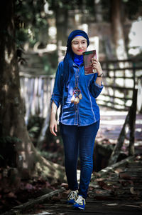 Portrait of young woman standing against trees