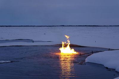 Bonfire on beach against sky at sunset