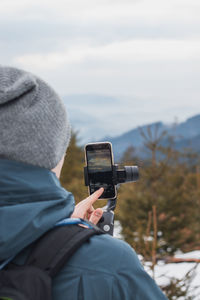 Rear view of man using mobile phone in winter