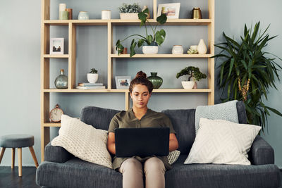 Full length of woman sitting on sofa at home