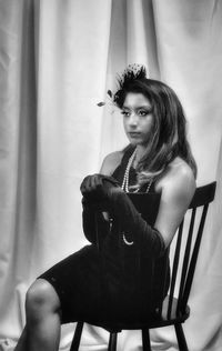 Portrait of young woman sitting on chair at home